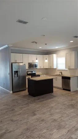 a large kitchen with cabinets a sink and stainless steel appliances