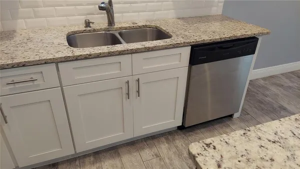 a kitchen with granite countertop white cabinets and a sink