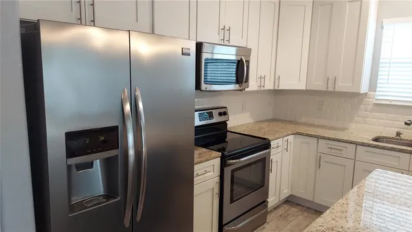 a kitchen with stainless steel appliances granite countertop a refrigerator and a sink