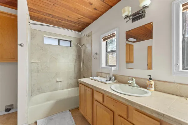 a bathroom with a granite countertop sink a mirror and a bathtub