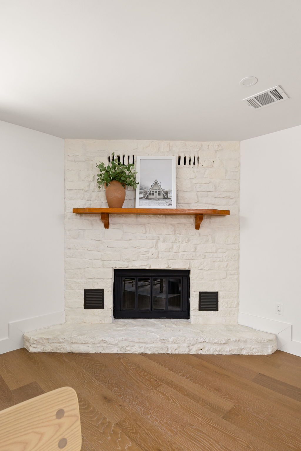 4501 Pack Saddle Pass Austin, TX 78745 - Photo 19 of 37 Corner fireplace with a painted stone facade, dark metal insert, and a wood mantel