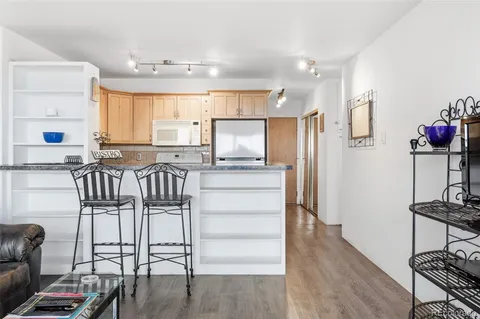 a kitchen with granite countertop a refrigerator cabinets and wooden floor