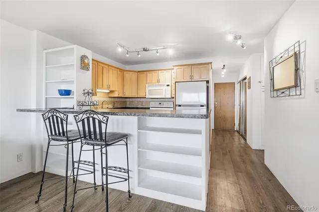 a kitchen with granite countertop a refrigerator stove microwave and cabinets