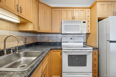 a kitchen with granite countertop a sink a stove and refrigerator