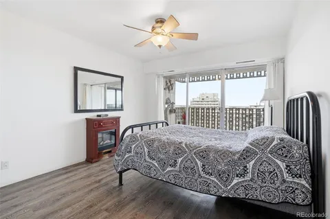 a bedroom with a bed painting on wall and a large window