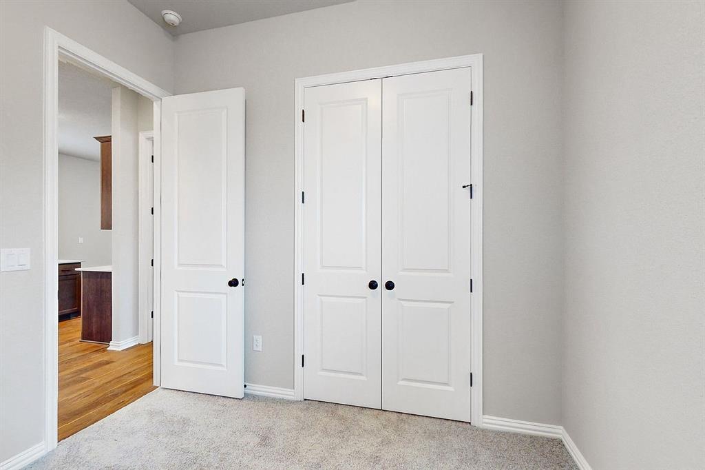 4907 Escape Rivera Drive Austin, TX 78747 - Photo 14 of 28 A well-lit bedroom with fresh gray walls, new carpet, and classic white paneled doors leading to a closet.