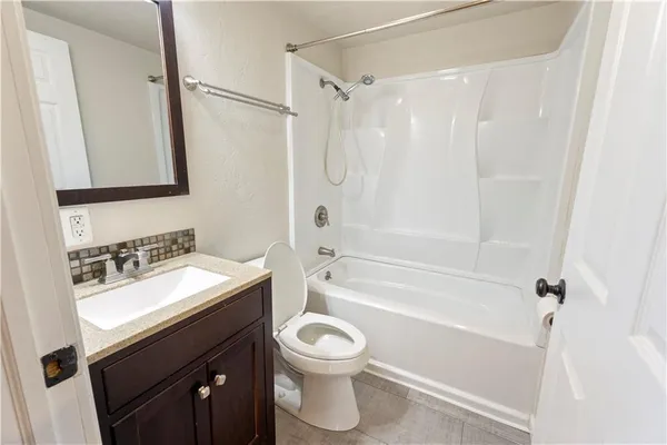 a bathroom with a bathtub shower sink vanity and toilet