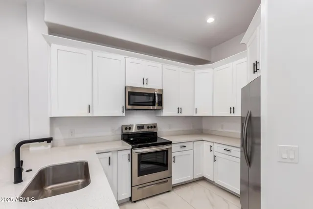a kitchen with white cabinets stainless steel appliances and sink