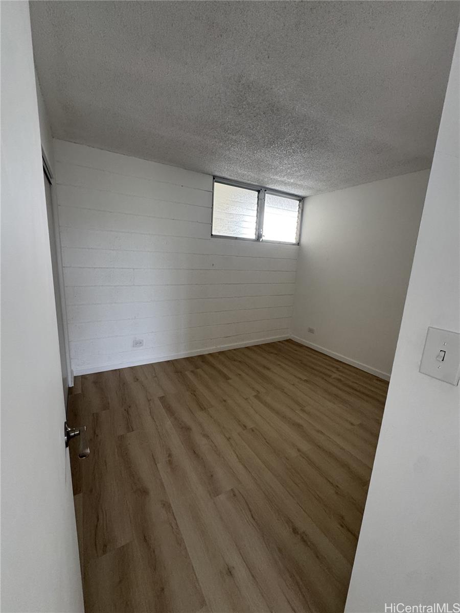 5210 Likini Street, Unit 1106 Honolulu, HI 96818 - Photo 6 of 7 an empty room with wooden floor and windows