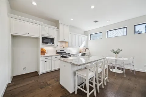 a kitchen with stainless steel appliances a table chairs sink and cabinets