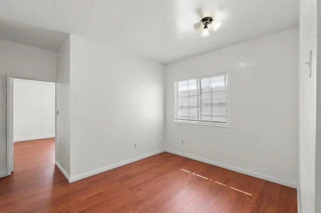 a view of an empty room with wooden floor and closet