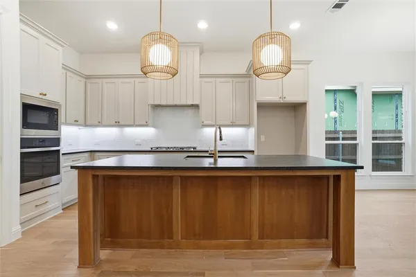 a large kitchen with granite countertop a stove a sink dishwasher a dining table and chair with wooden floor