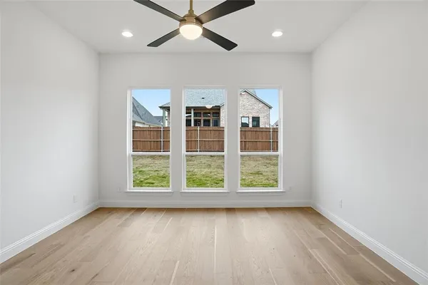an empty room with wooden floor fan and windows