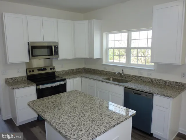 a kitchen with granite countertop a sink a counter top space and appliances