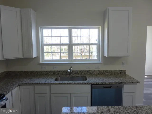a kitchen with granite countertop a sink stove and cabinets