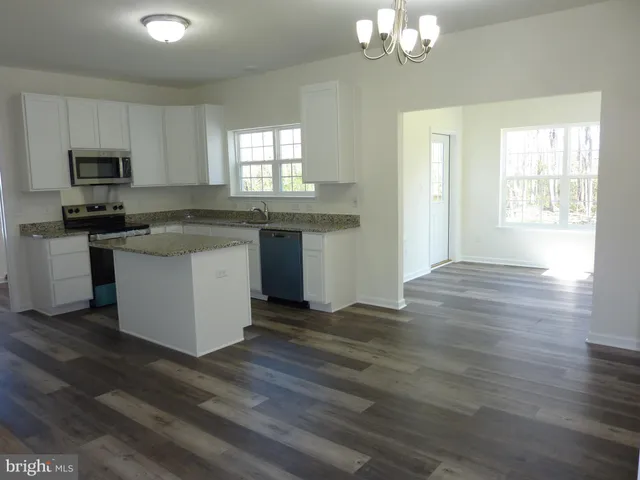 a kitchen with stainless steel appliances granite countertop a stove top oven a sink dishwasher a refrigerator and white cabinets with wooden floor