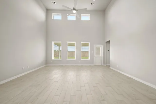 a view of an empty room with chandelier fan and wooden floor