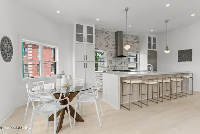 a kitchen with kitchen island a dining table chairs sink and cabinets