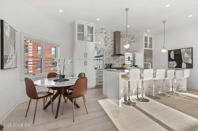 a kitchen with stainless steel appliances kitchen island granite countertop a dining table chairs and a white refrigerator