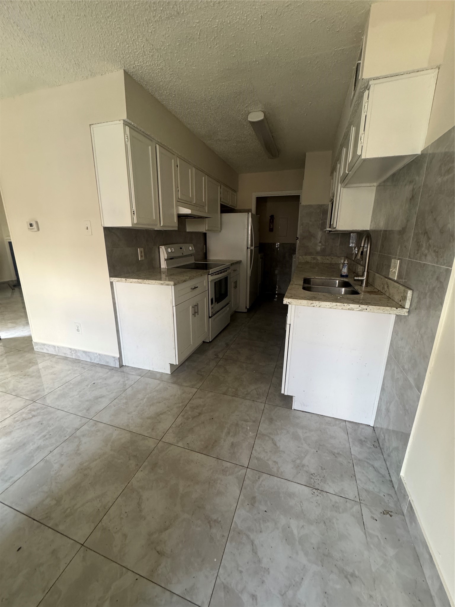 12700 Leader Street, Unit B Houston, TX 77072 - Photo 5 of 7 a kitchen with a sink a stove top oven and white cabinets