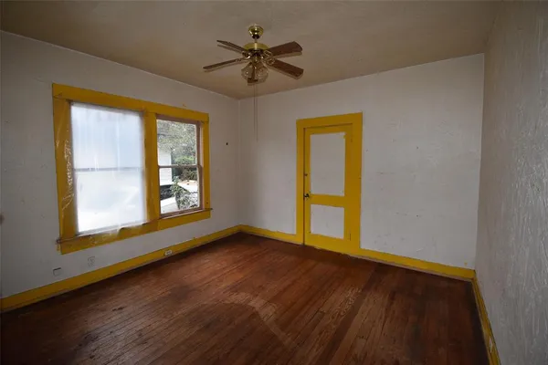 a view of an empty room with a window and wooden floor