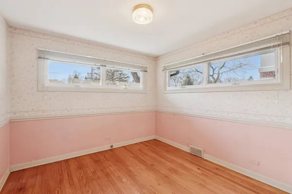 a view of an empty room with wooden floor and window