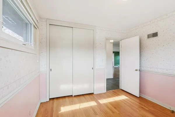 a view of an empty room with closet and a window