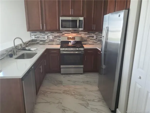 a kitchen with stainless steel appliances a stove a sink and a refrigerator with wooden floor