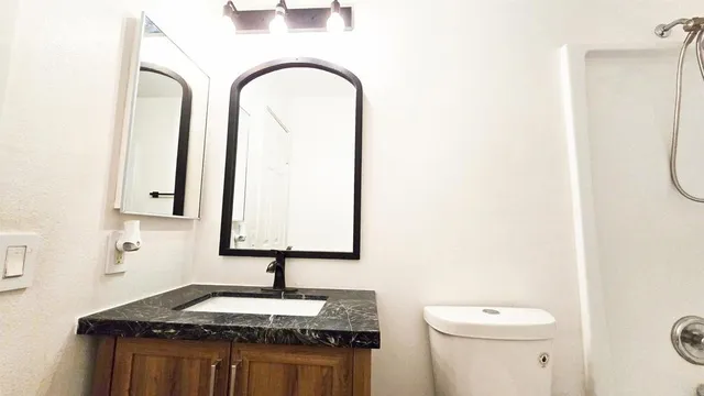a bathroom with a granite countertop sink and a toilet