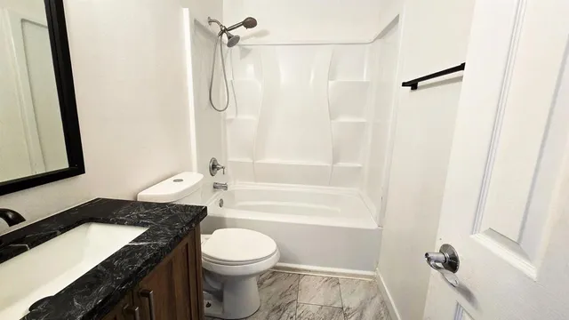 a bathroom with a granite countertop sink toilet and shower
