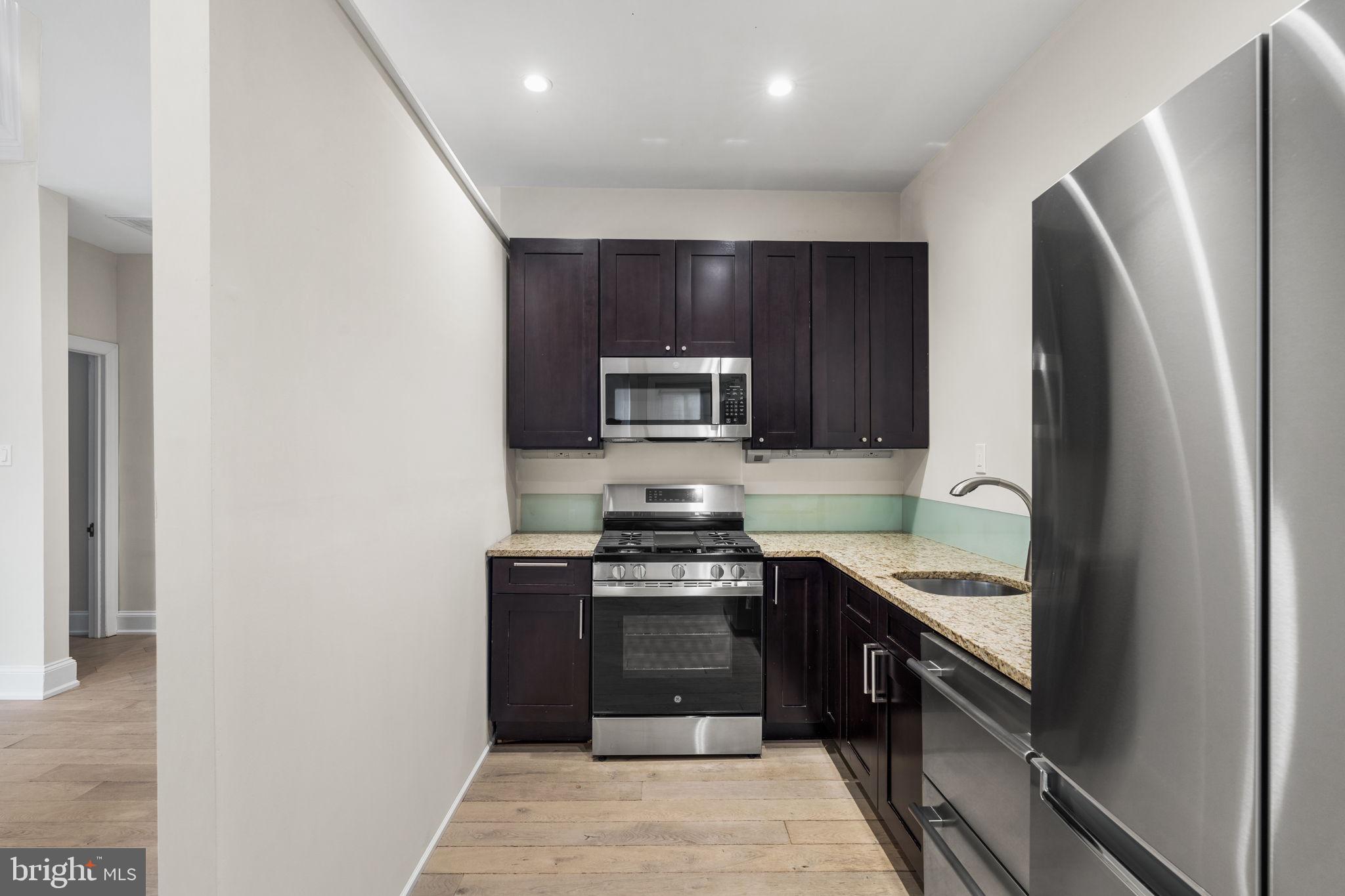 1830 Rittenhouse Square, Unit 1C Philadelphia, PA 19103 - Photo 12 of 32 a kitchen with stainless steel appliances granite countertop a refrigerator and a stove top oven