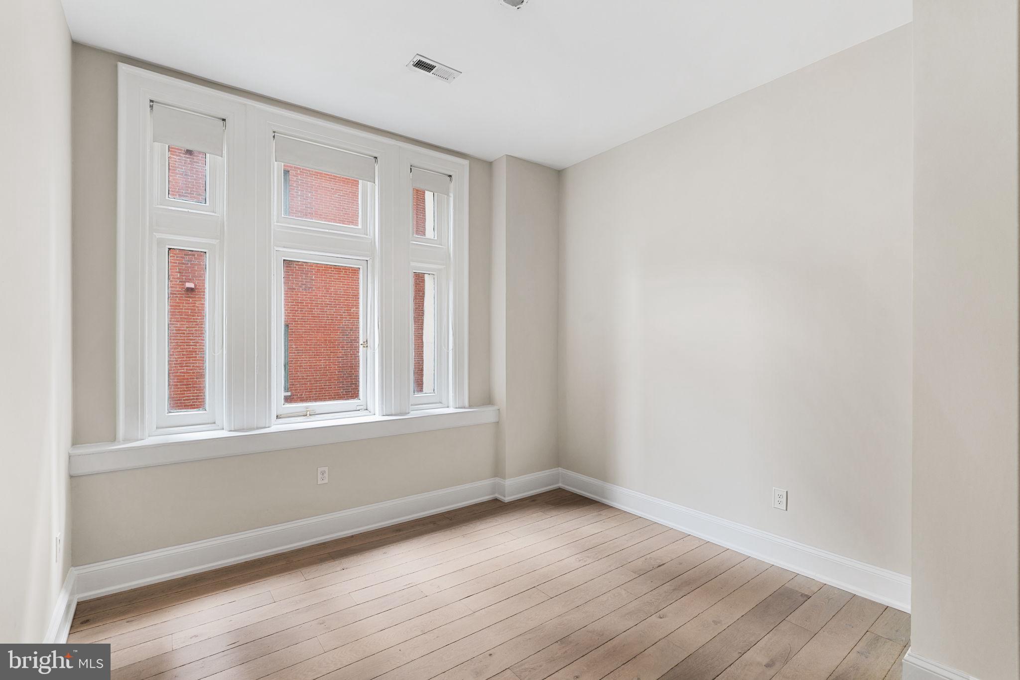 1830 Rittenhouse Square, Unit 1C Philadelphia, PA 19103 - Photo 18 of 32 an empty room with wooden floor and windows