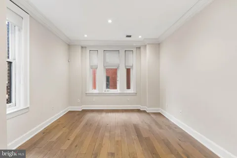a view of empty room with wooden floor and fan