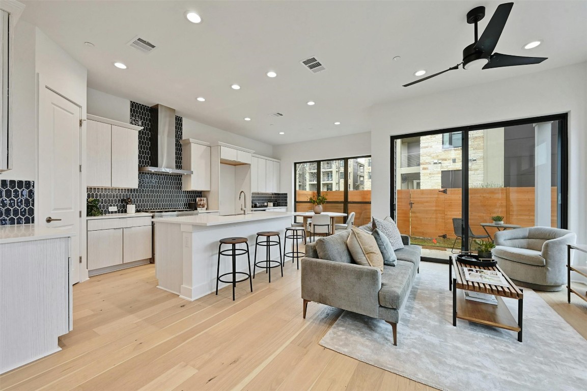 a kitchen with white cabinets and black stainless steel appliances with a living room