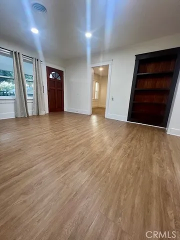 an empty room with wooden floor and window
