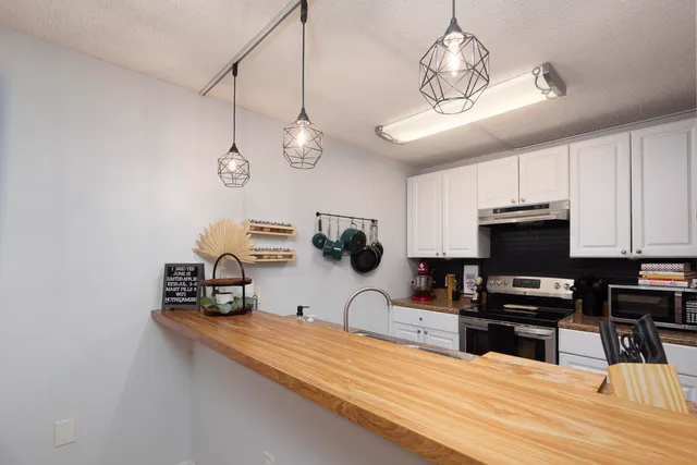 a kitchen with kitchen island granite countertop stainless steel appliances cabinets a sink and a stove