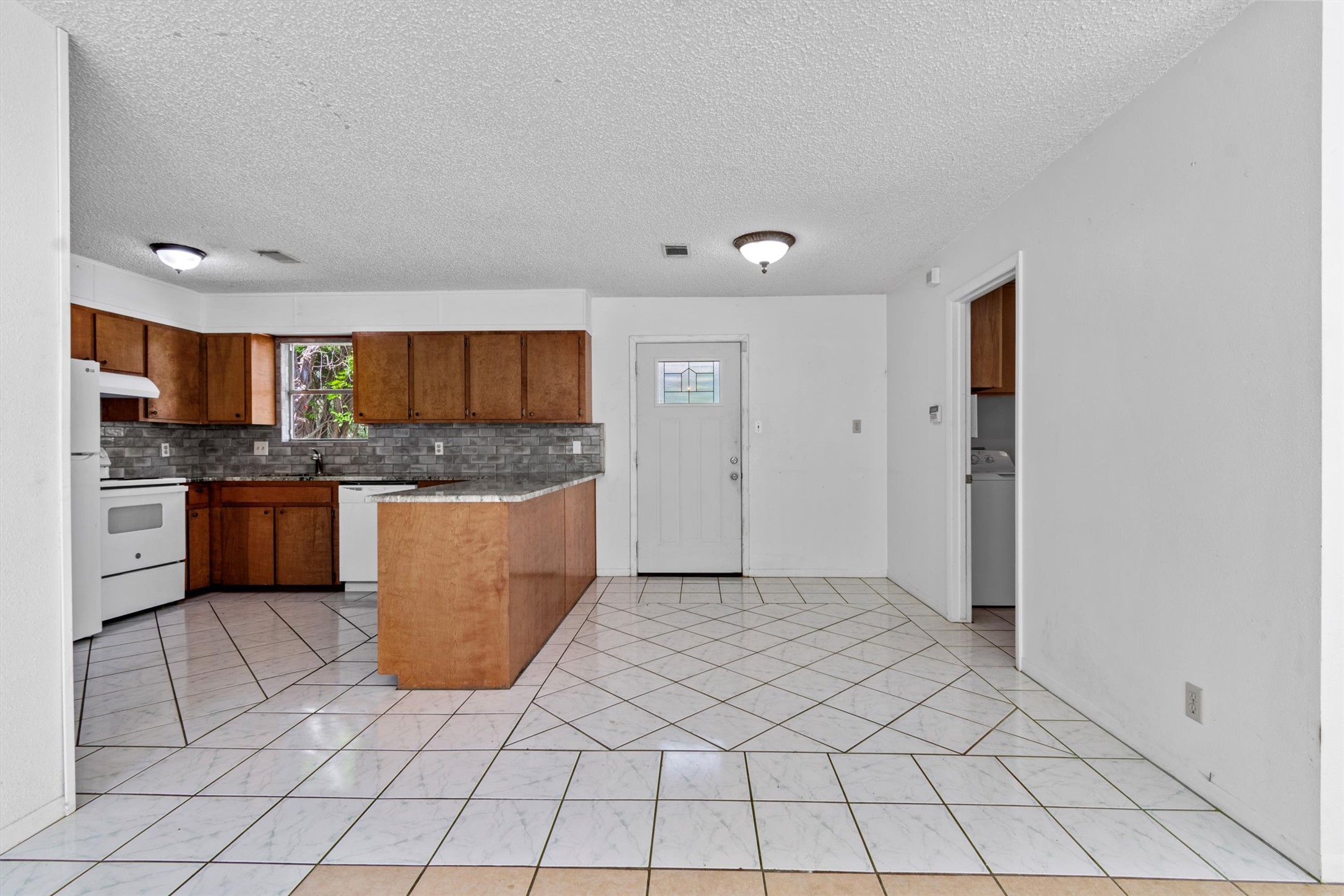 6 El Sol Road Wimberley, TX 78676 - Photo 5 of 20 A well-lit kitchen with sleek tile flooring and ample cabinetry for storage.