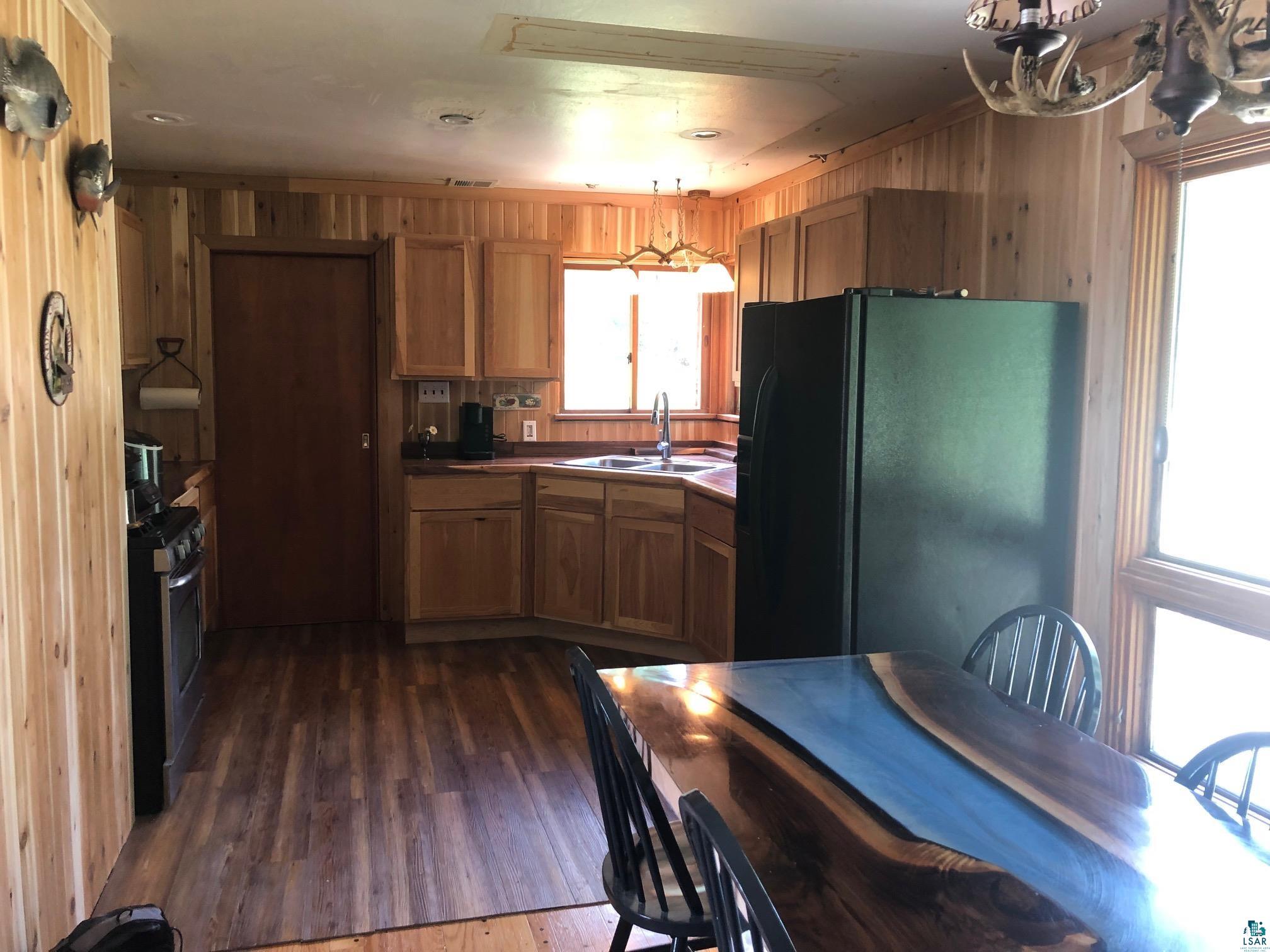 444 Fernberg Road, Unit 11 Ely, MN 55731 - Photo 7 of 19 Kitchen featuring freestanding refrigerator, a sink, wooden walls, and plenty of natural light