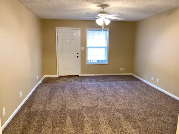 an empty room with windows and fan