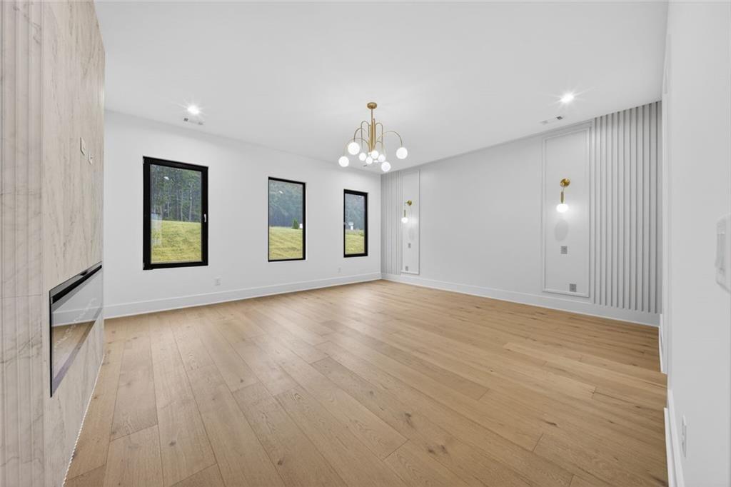 125 Rocky Rdg Way Auburn, GA 30011 - Photo 26 of 68 an empty room with wooden floor chandelier and windows