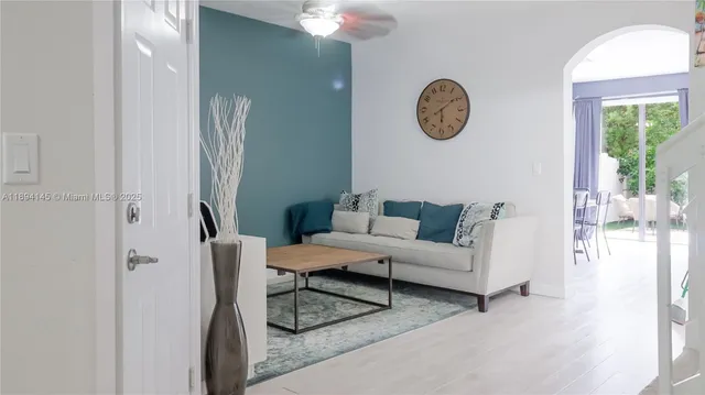a living room with furniture a floor to ceiling window and a mirror