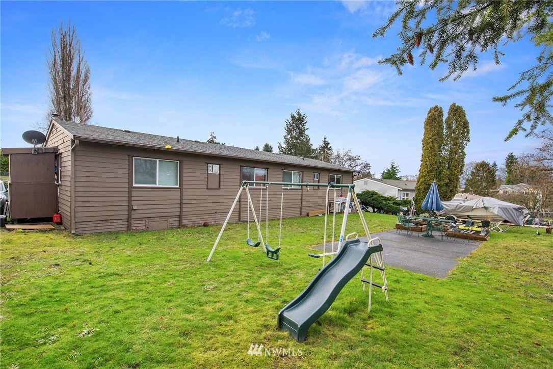 2906 Northeast 6th Place Renton, WA 98056 - Photo 5 of 21 a view of a backyard with a slide trees and wooden fence