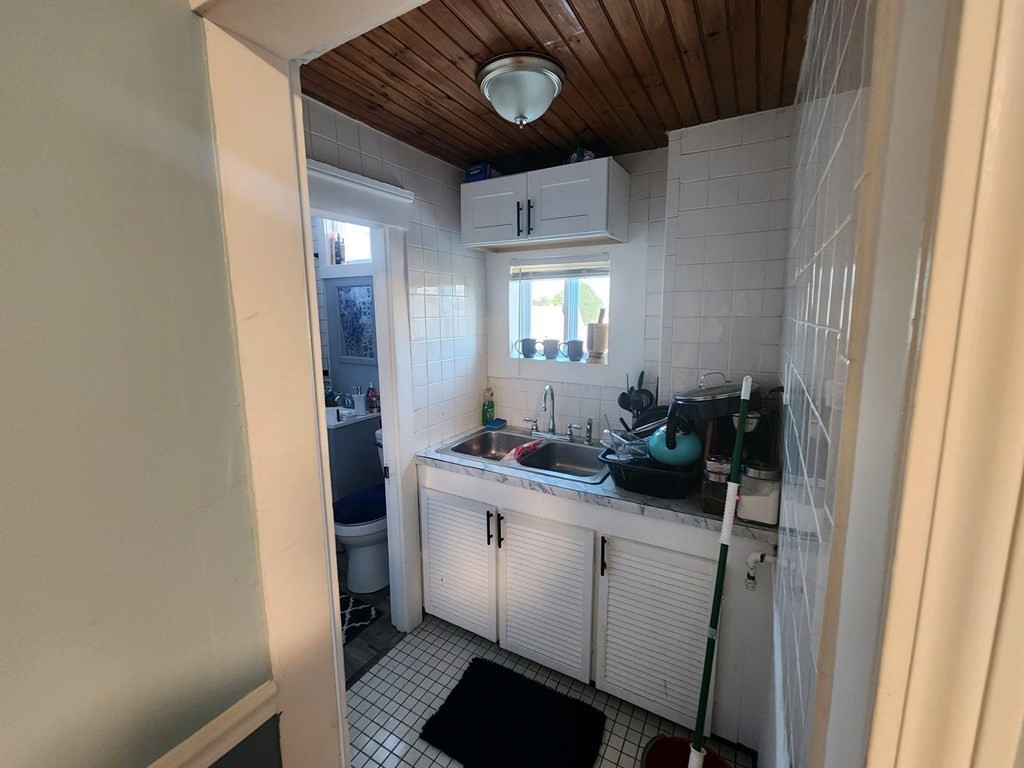 28 Frederick Street New Bedford, MA 02744 - Photo 18 of 29 a hallway with a sink and a mirror