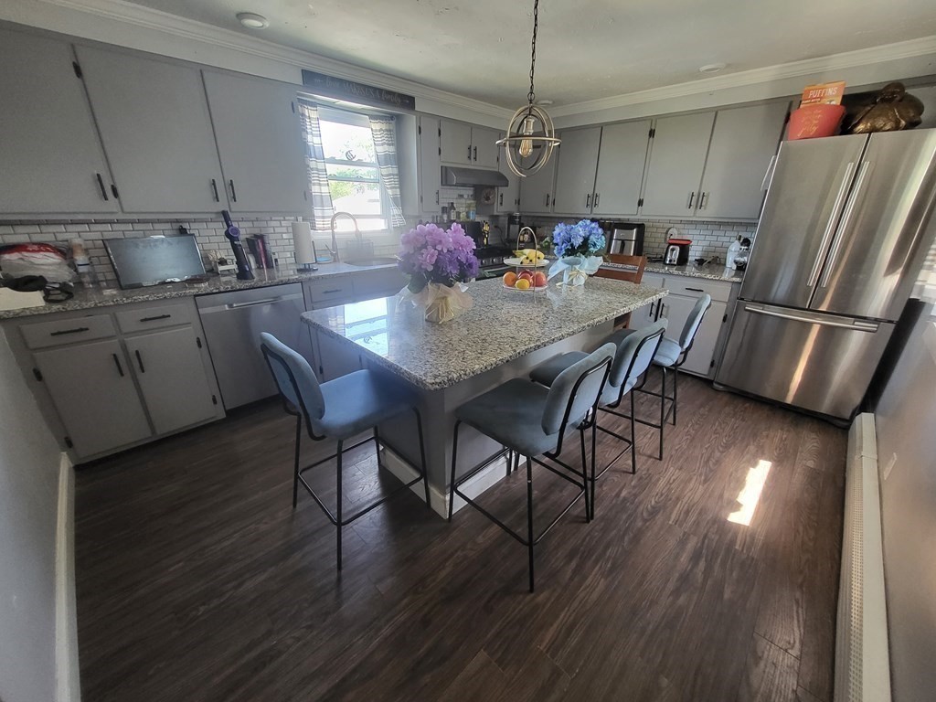 28 Frederick Street New Bedford, MA 02744 - Photo 8 of 29 a kitchen with stainless steel appliances granite countertop a refrigerator a stove a sink dishwasher a dining table and chairs with wooden floor