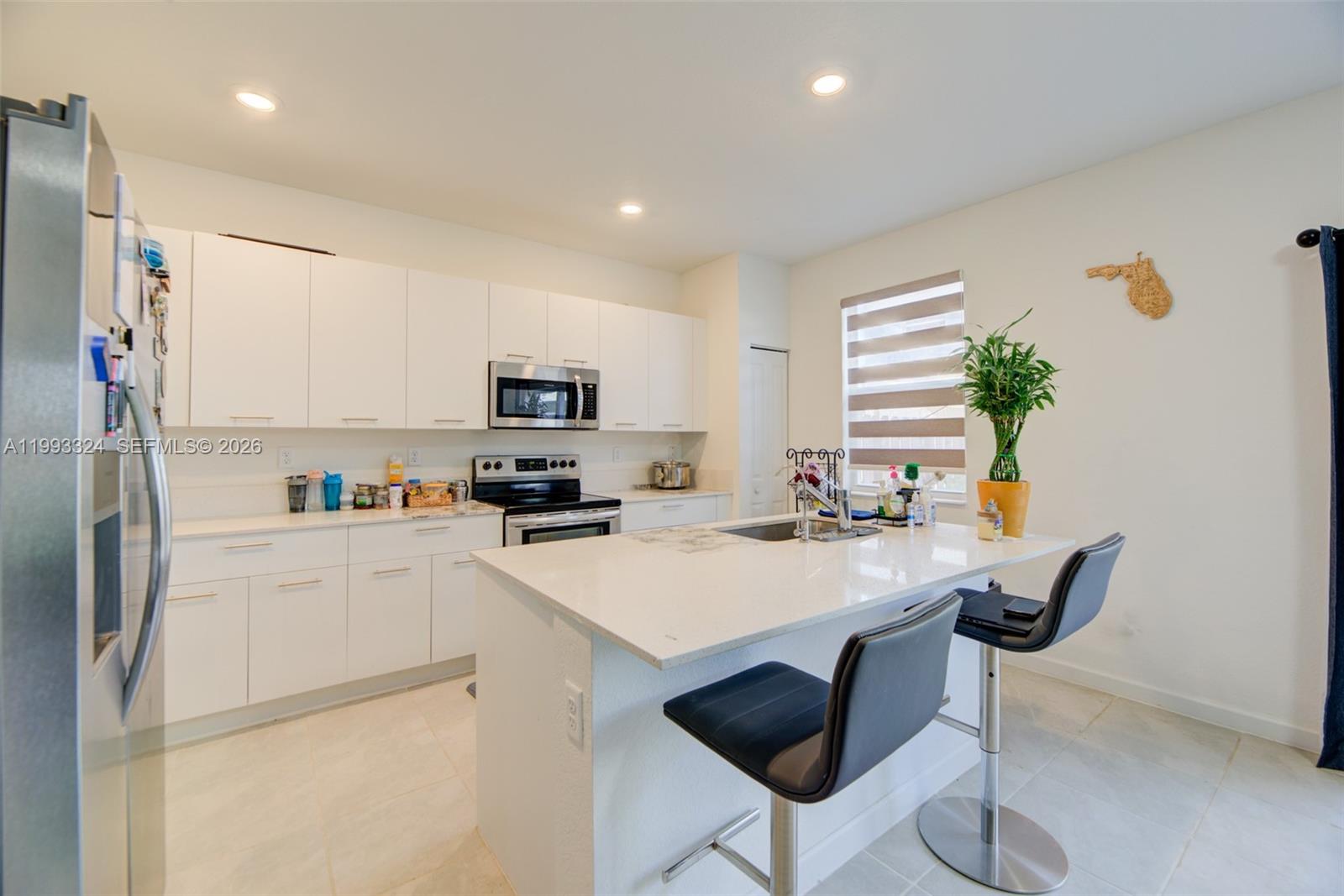 12604 Northwest 23rd Place Miami, FL 33167 - Photo 13 of 39 a kitchen with stainless steel appliances a stove a refrigerator white cabinets and a dining table