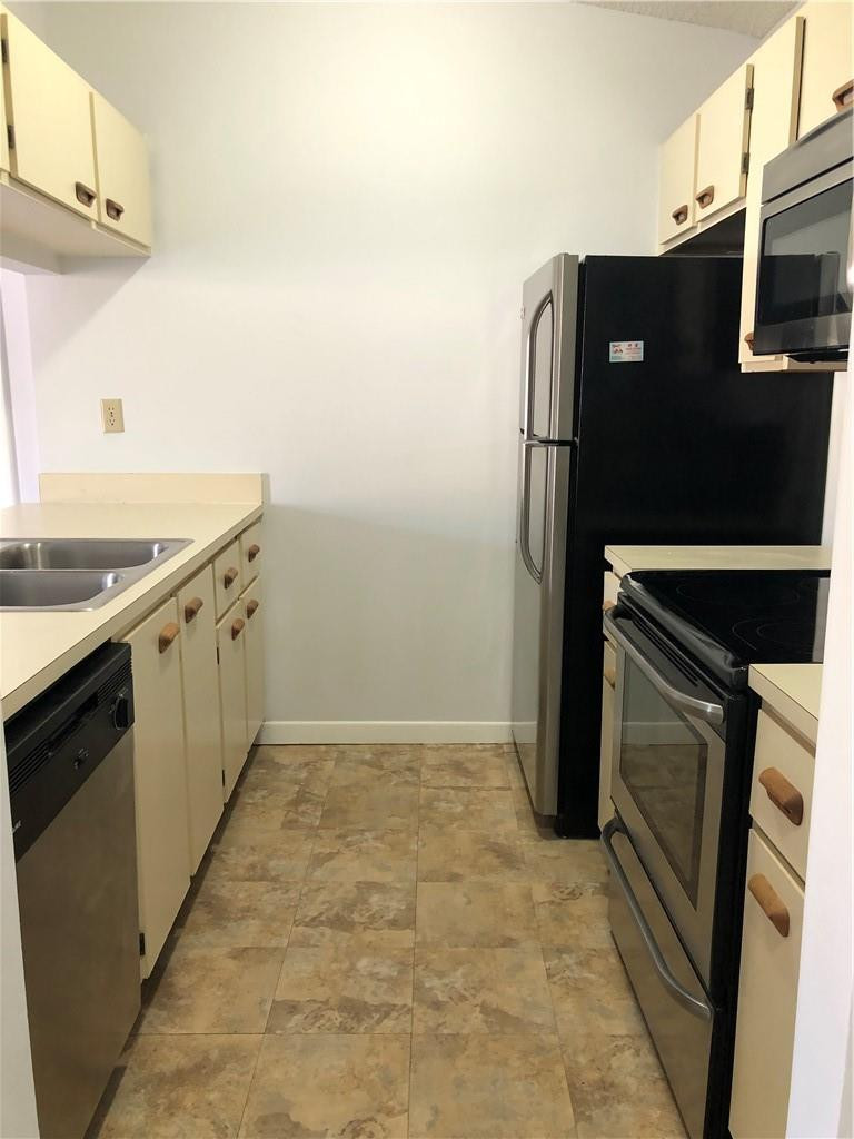 9466 Boca Cove Circle, Unit 313 Boca Raton, FL 33428 - Photo 3 of 7 a kitchen with stainless steel appliances granite countertop a refrigerator and a stove