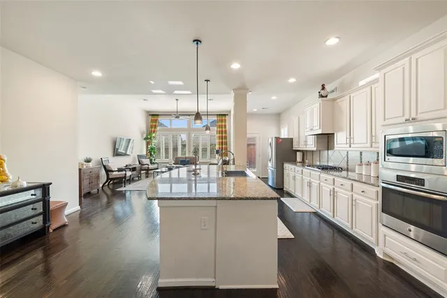 a kitchen with stainless steel appliances granite countertop a sink a stove and a wooden floor