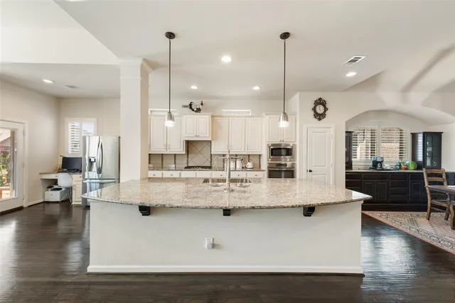 an open kitchen with kitchen island white cabinets and stainless steel appliances