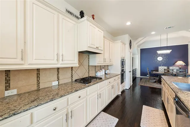 a large white kitchen with kitchen island a large counter top appliances and a living room view