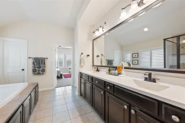 a bathroom with a tub a sink and a large mirror